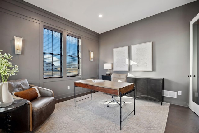 office featuring wood finished floors, visible vents, and baseboards