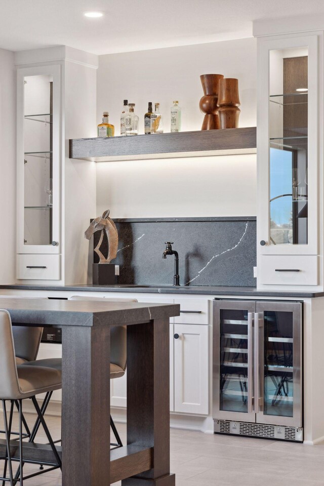 bar with beverage cooler, indoor wet bar, and backsplash