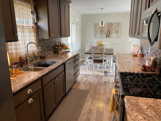 kitchen with appliances with stainless steel finishes, a textured ceiling, dark hardwood / wood-style floors, decorative light fixtures, and sink