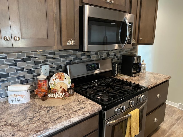 kitchen featuring backsplash, appliances with stainless steel finishes, dark brown cabinetry, and light hardwood / wood-style floors