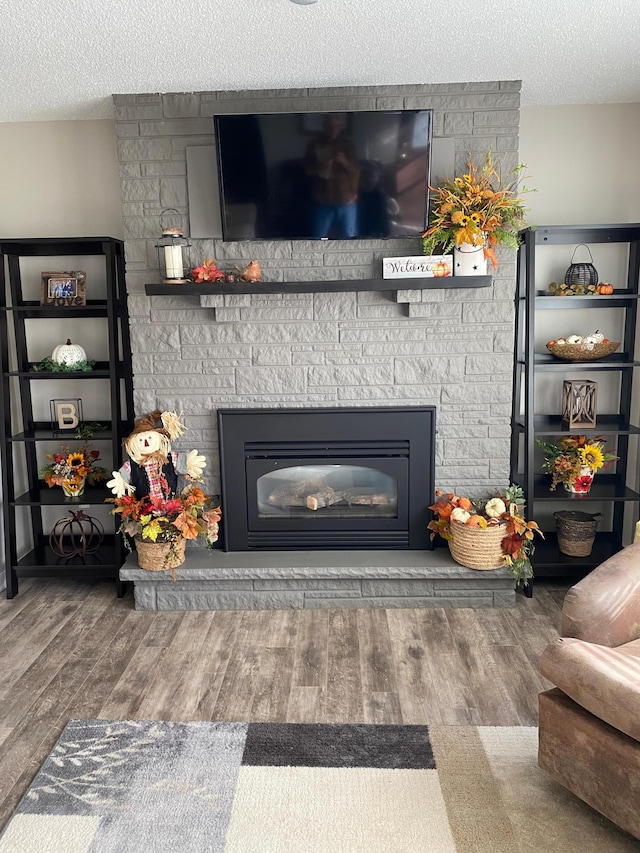 details with a stone fireplace, a textured ceiling, and hardwood / wood-style floors