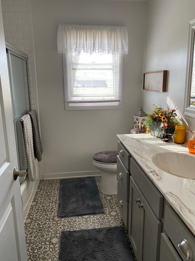 bathroom with vanity, toilet, tile patterned floors, and a shower with shower door