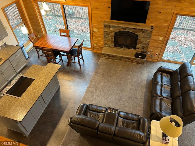 living room featuring a stone fireplace and wooden walls