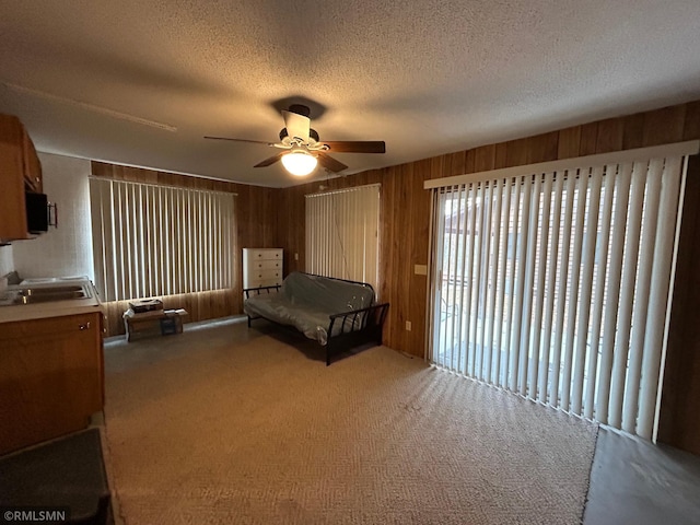 unfurnished bedroom featuring wooden walls, a textured ceiling, carpet, and ceiling fan