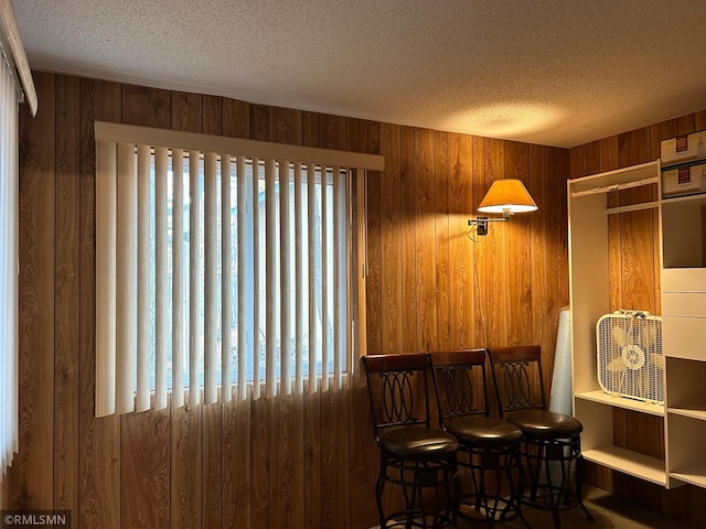 dining room with wood walls, indoor bar, and a textured ceiling