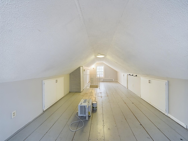 bonus room with light hardwood / wood-style floors, vaulted ceiling, a textured ceiling, and a baseboard radiator