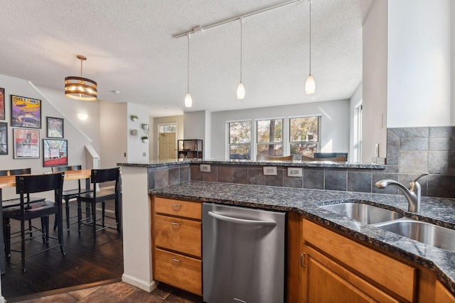 kitchen with dark stone countertops, sink, pendant lighting, and a textured ceiling