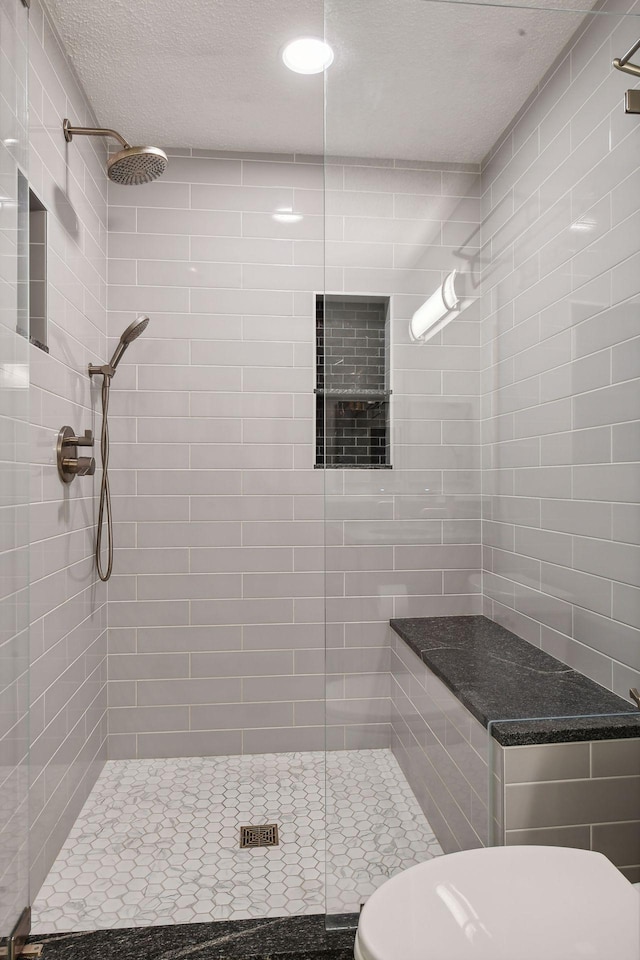 bathroom featuring a tile shower, a textured ceiling, and toilet