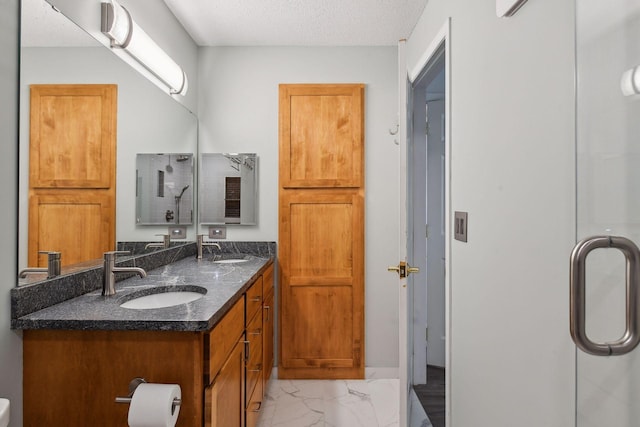 bathroom featuring vanity, a shower with door, and a textured ceiling