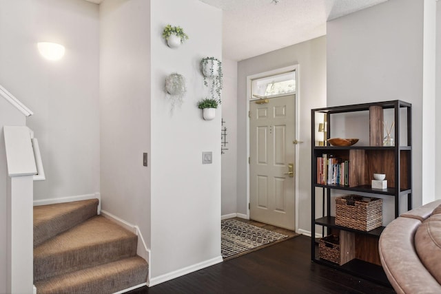 foyer entrance with dark hardwood / wood-style floors and a textured ceiling