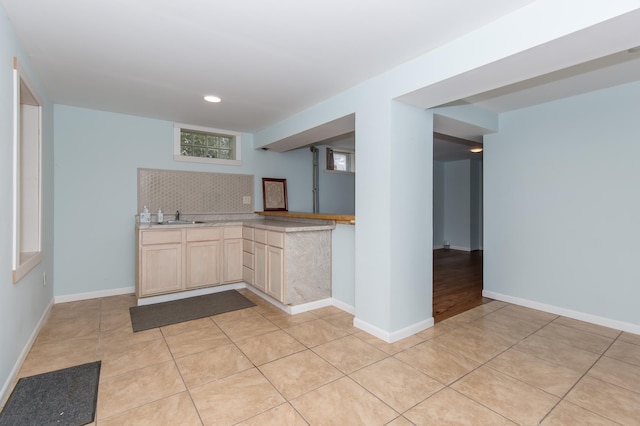 kitchen featuring decorative backsplash, sink, light tile patterned flooring, and light brown cabinets