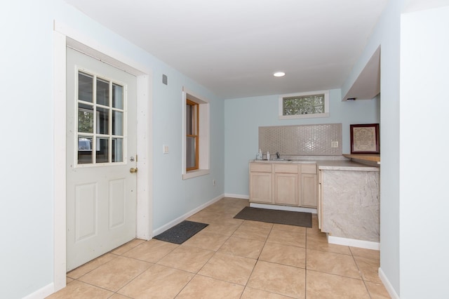 kitchen with light brown cabinets, sink, backsplash, and light tile patterned flooring