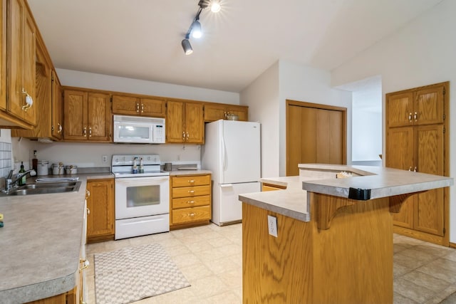 kitchen featuring a breakfast bar, white appliances, a center island with sink, sink, and vaulted ceiling