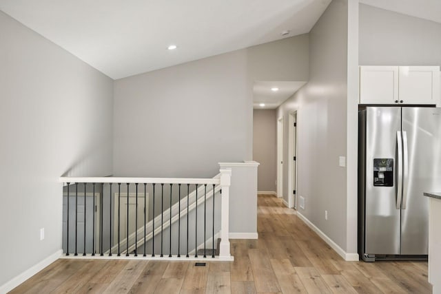 hall with light hardwood / wood-style flooring and vaulted ceiling