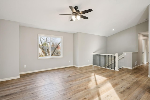 spare room featuring light hardwood / wood-style flooring, vaulted ceiling, and ceiling fan