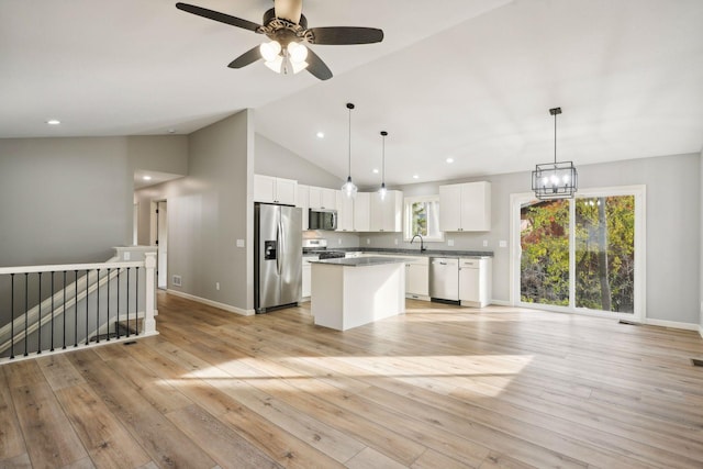 kitchen with appliances with stainless steel finishes, white cabinets, a kitchen island, and light hardwood / wood-style floors