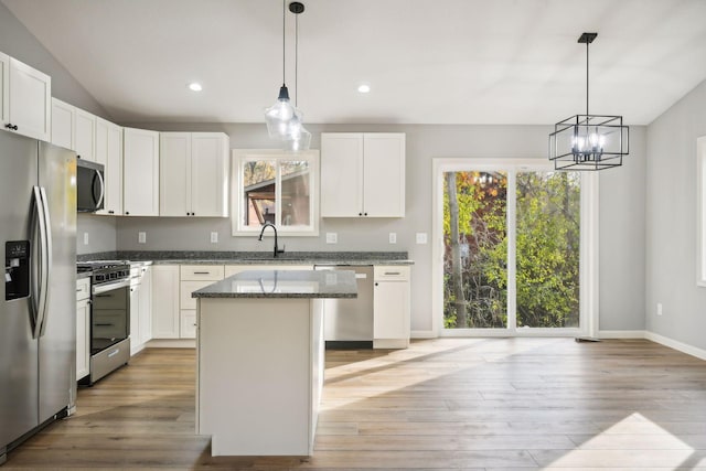 kitchen with a kitchen island, appliances with stainless steel finishes, hanging light fixtures, and white cabinetry