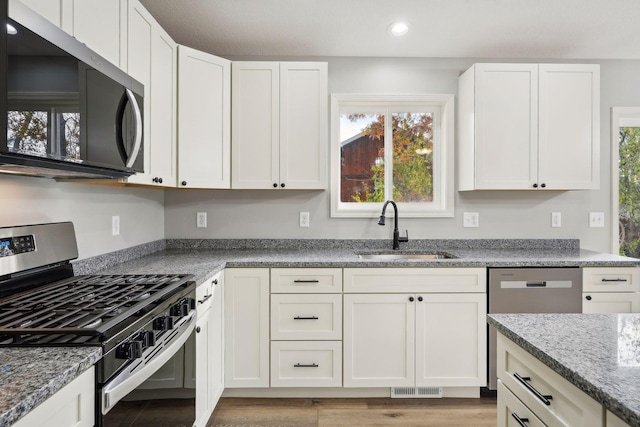 kitchen with appliances with stainless steel finishes, sink, and white cabinets