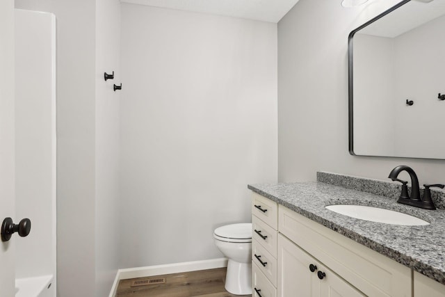 bathroom with vanity, toilet, and hardwood / wood-style flooring