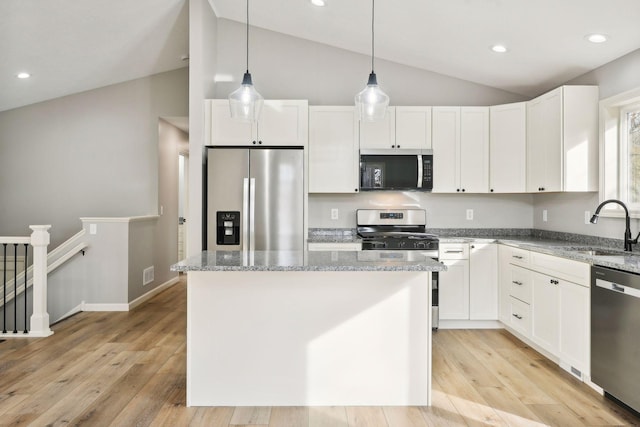 kitchen with appliances with stainless steel finishes, sink, a center island, white cabinetry, and vaulted ceiling