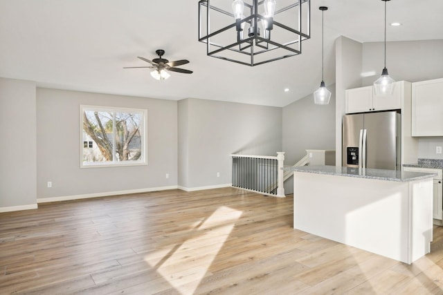 kitchen with light stone counters, vaulted ceiling, white cabinets, and stainless steel refrigerator with ice dispenser