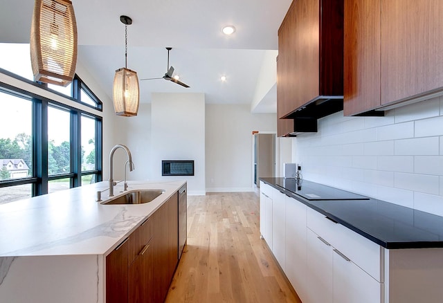 kitchen featuring pendant lighting, lofted ceiling, backsplash, sink, and white cabinetry