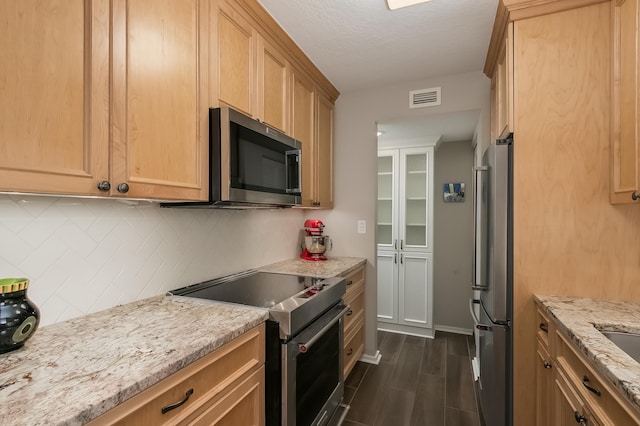 kitchen with light stone countertops, appliances with stainless steel finishes, dark hardwood / wood-style flooring, tasteful backsplash, and light brown cabinets