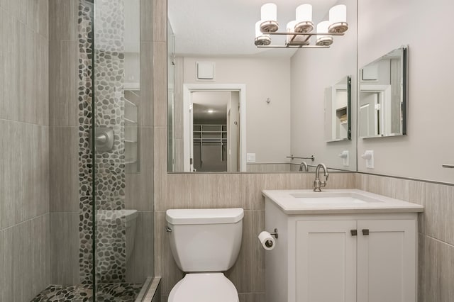 bathroom featuring vanity, toilet, a shower with shower door, and tile walls