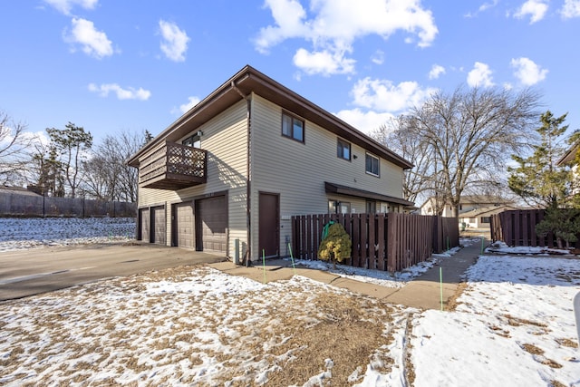 snow covered property with a garage and a balcony