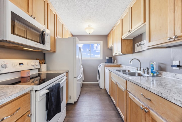 kitchen featuring light brown cabinetry, sink, white appliances, washing machine and clothes dryer, and a textured ceiling