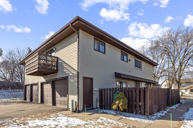 snow covered property featuring a garage and a balcony