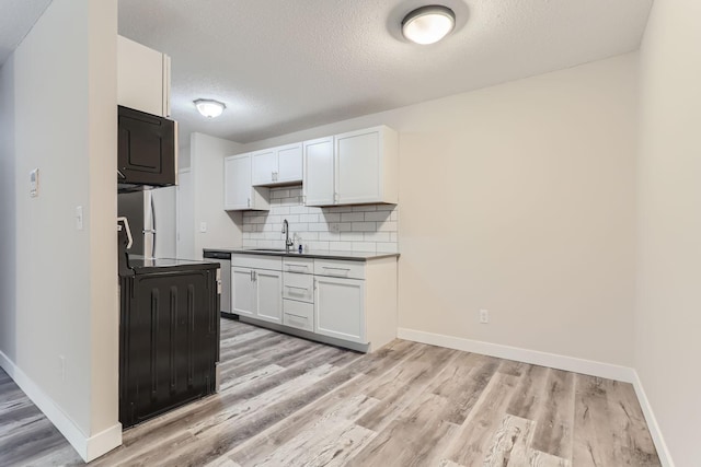 kitchen featuring decorative backsplash, white cabinets, appliances with stainless steel finishes, light hardwood / wood-style floors, and sink