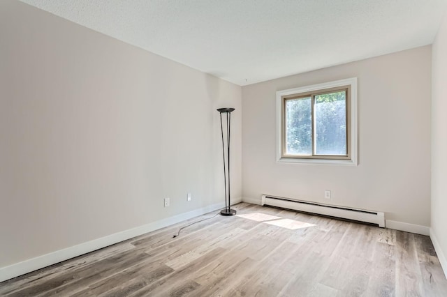 empty room with light hardwood / wood-style flooring, a textured ceiling, and a baseboard heating unit