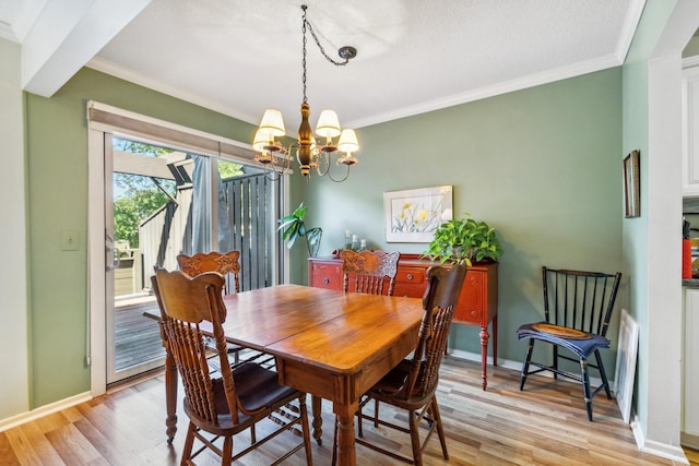 dining room with crown molding, a notable chandelier, a textured ceiling, and light hardwood / wood-style floors