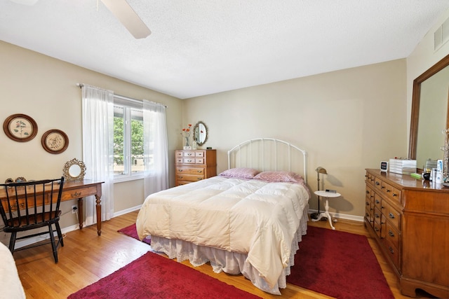 bedroom with hardwood / wood-style floors, a textured ceiling, and ceiling fan