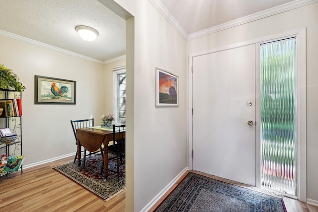 entrance foyer featuring a textured ceiling, light hardwood / wood-style flooring, and ornamental molding