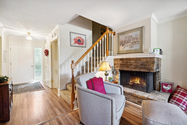 living room featuring a textured ceiling, crown molding, a fireplace, and light wood-type flooring