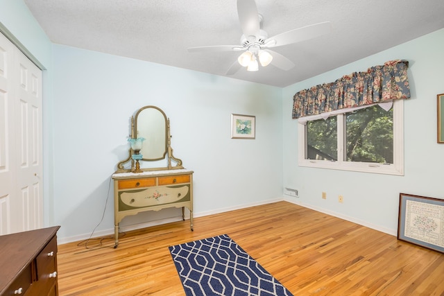 sitting room with hardwood / wood-style floors, a textured ceiling, and ceiling fan