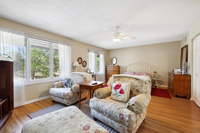 bedroom featuring light hardwood / wood-style flooring, a textured ceiling, and ceiling fan