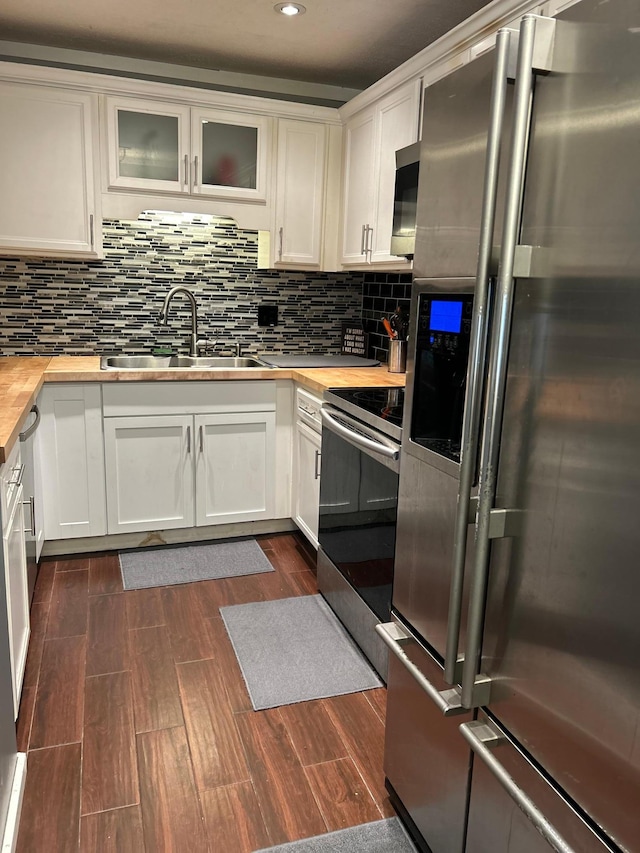 kitchen with white cabinetry, stainless steel appliances, sink, and butcher block countertops