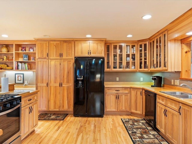 kitchen featuring sink, light hardwood / wood-style floors, and black appliances