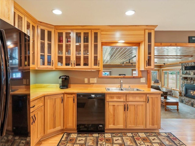 kitchen featuring sink, a fireplace, black appliances, and light hardwood / wood-style floors