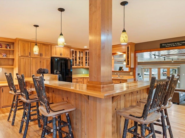 kitchen featuring wooden counters, sink, black refrigerator with ice dispenser, and light wood-type flooring