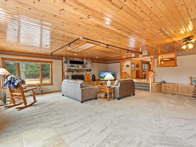 living room with light carpet, a stone fireplace, wooden ceiling, and rail lighting