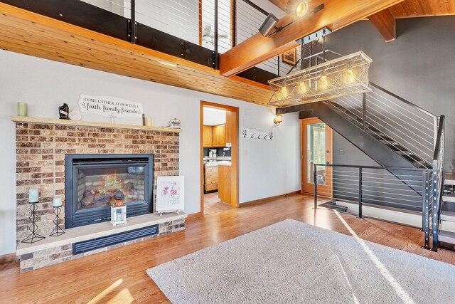 living room with a brick fireplace, hardwood / wood-style floors, beamed ceiling, and high vaulted ceiling