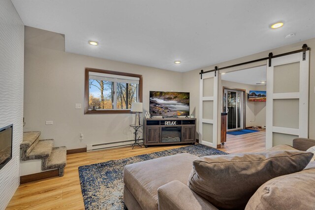 living room featuring a barn door, light hardwood / wood-style floors, and a baseboard radiator