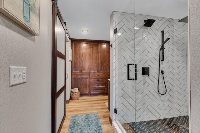 bathroom with hardwood / wood-style flooring and a shower with shower door