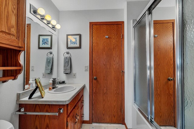 full bathroom with vanity, combined bath / shower with glass door, and toilet