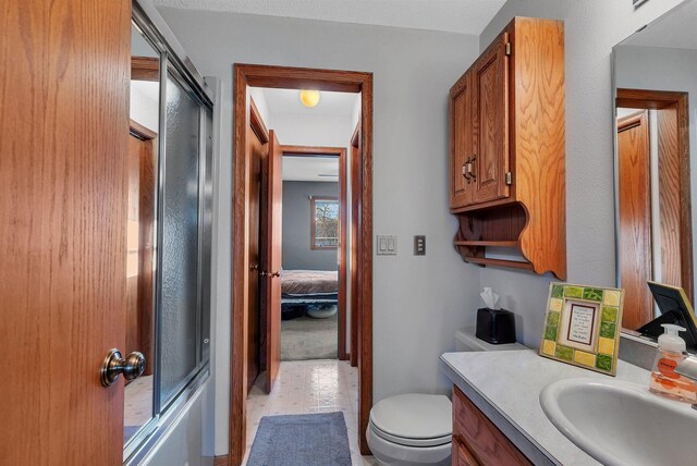 full bathroom with enclosed tub / shower combo, toilet, and vanity