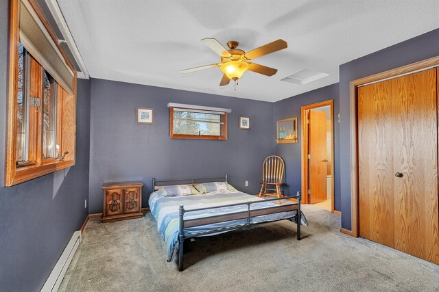 carpeted bedroom with a closet, connected bathroom, a textured ceiling, a baseboard heating unit, and ceiling fan